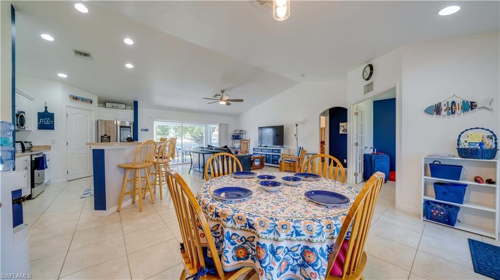 Dining space with recessed lighting, lofted ceiling, arched walkways, light tile patterned floors, and a ceiling fan