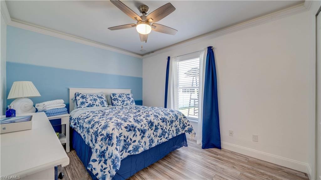 Bedroom with ornamental molding, light wood-style flooring, and a ceiling fan