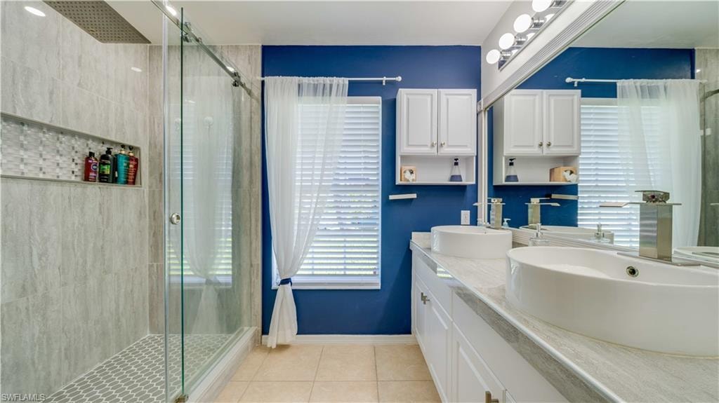 Bathroom with light tile patterned flooring, double vanity, and a shower stall