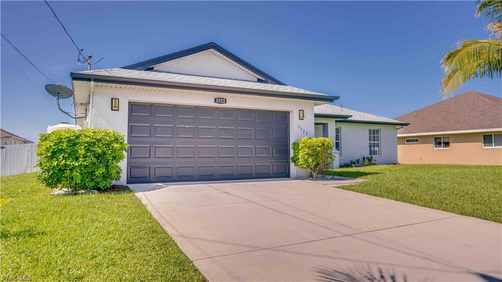 Ranch-style house featuring a front lawn, concrete driveway, stucco siding, and a garage
