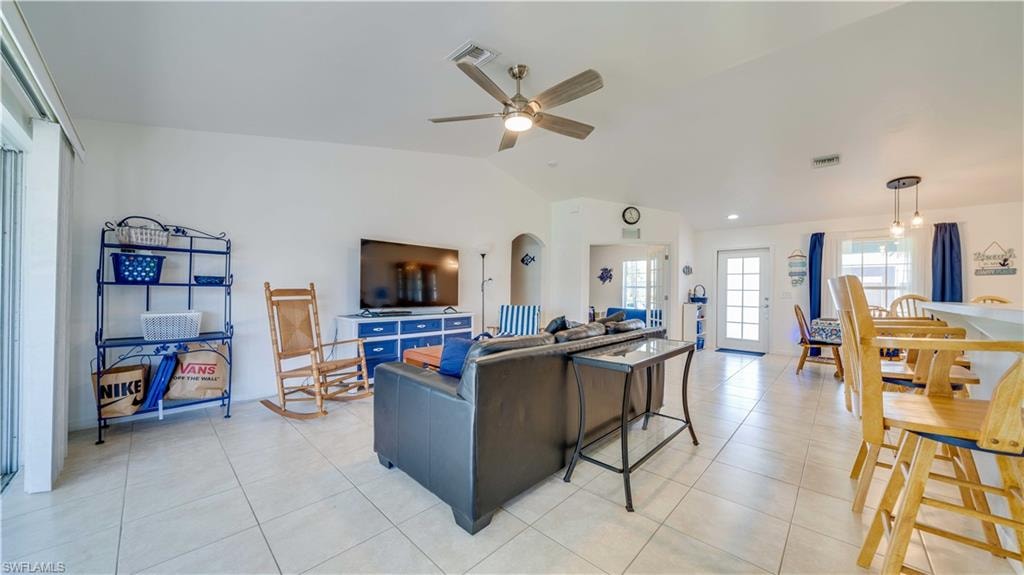 Living room featuring vaulted ceiling, light tile patterned floors, and ceiling fan