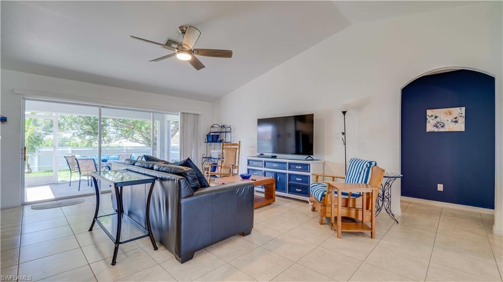 Living room featuring ceiling fan, arched walkways, light tile patterned floors, and high vaulted ceiling
