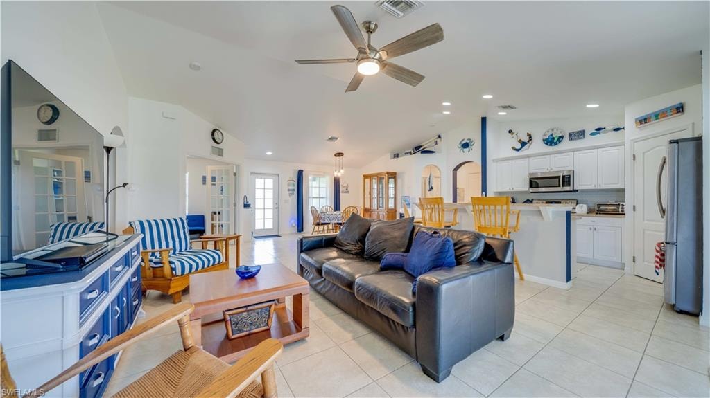 Living area with light tile patterned floors, ceiling fan, recessed lighting, high vaulted ceiling, and arched walkways