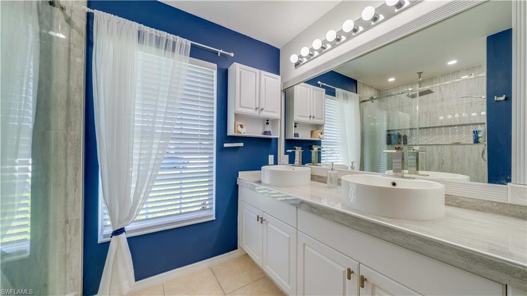 Bathroom featuring light tile patterned flooring, a shower stall, and double vanity