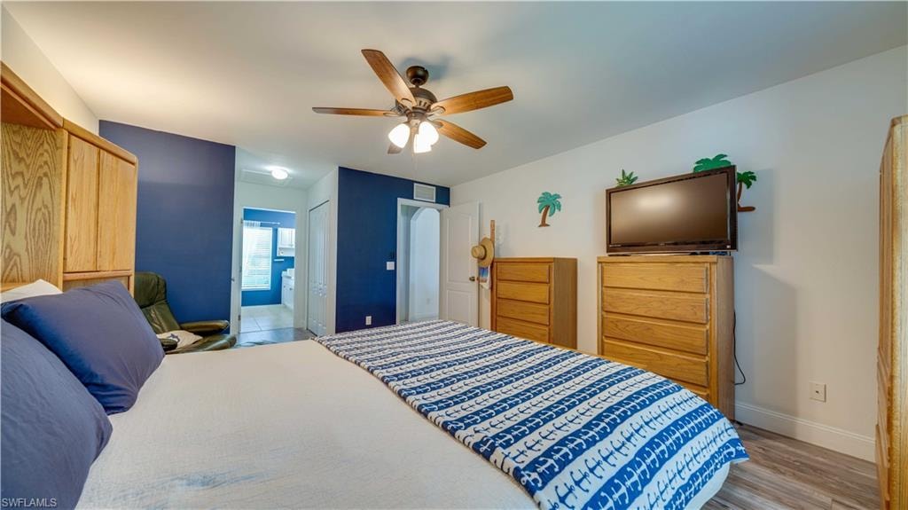 Bedroom featuring connected bathroom, a closet, light wood-type flooring, and ceiling fan