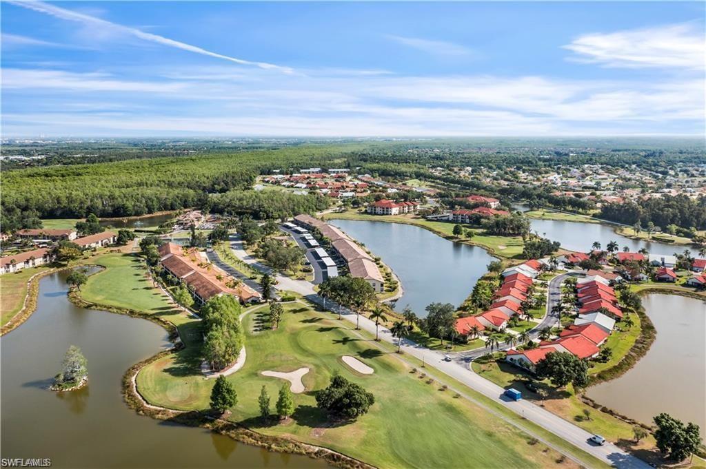 Aerial view of property and surrounding area with a golf club, a nearby body of water, and nearby suburban area