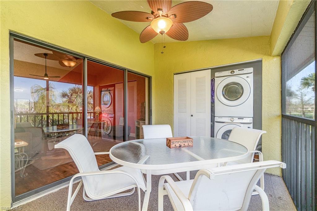 Sunroom with vaulted ceiling, outdoor dining area, a ceiling fan, and stacked washing machine and dryer