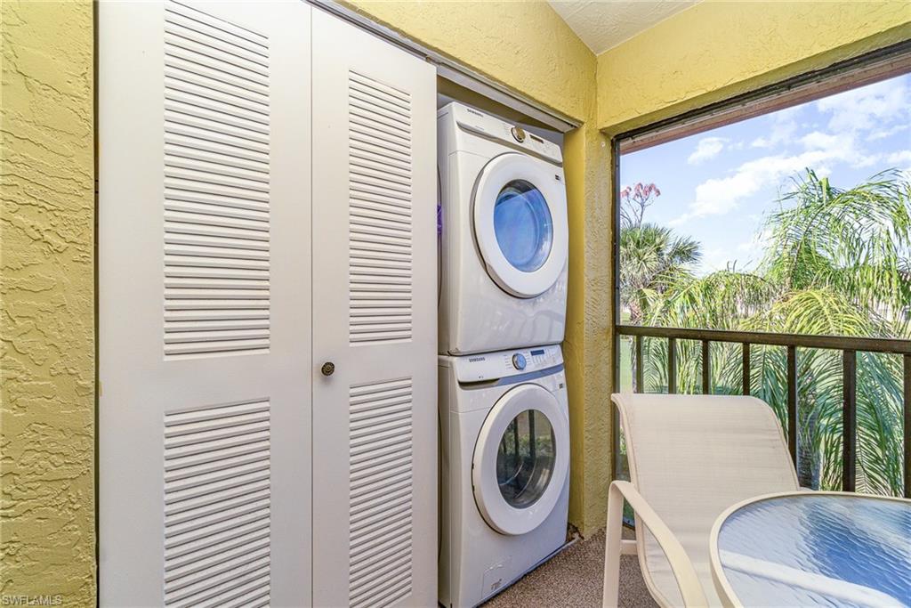 Laundry area with a textured wall and stacked washing machine and dryer