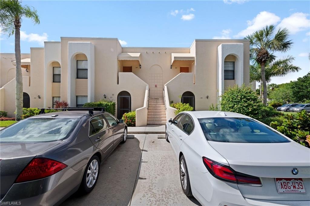 Mediterranean / spanish house with uncovered parking, stucco siding, and stairs
