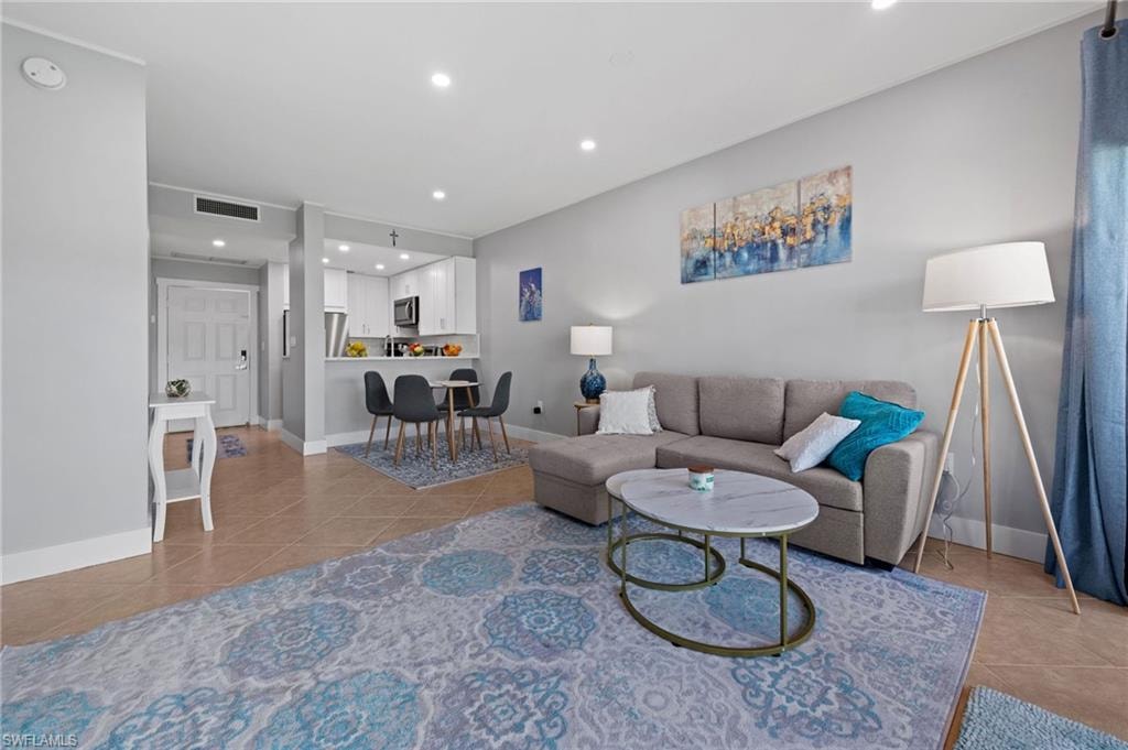 Living room with light tile patterned floors and recessed lighting