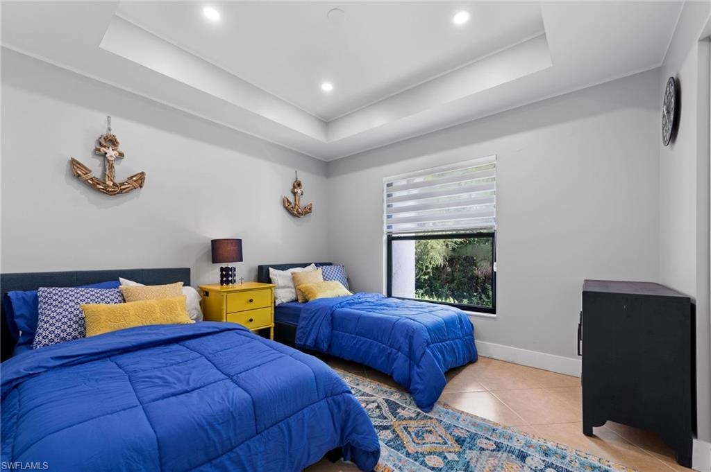 Tiled bedroom featuring a tray ceiling and recessed lighting