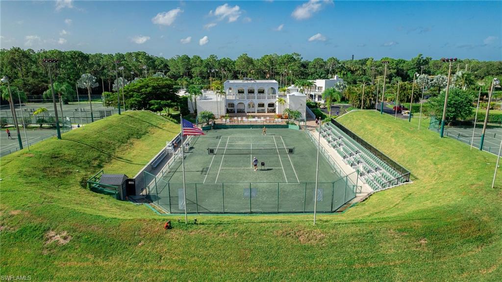 View of tennis court with view of wooded area