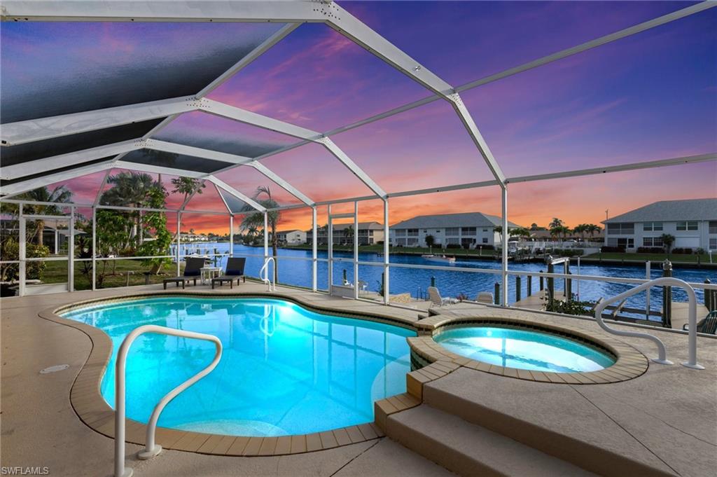 View of swimming pool with a water view, a lanai, a patio area, a pool with connected hot tub, and a sunroom