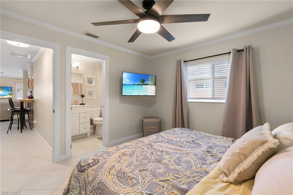 Bedroom featuring crown molding, light tile patterned flooring, ceiling fan, and ensuite bathroom