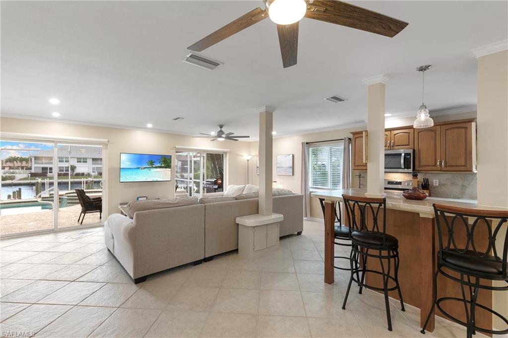 Living room with crown molding, light tile patterned floors, recessed lighting, and ceiling fan