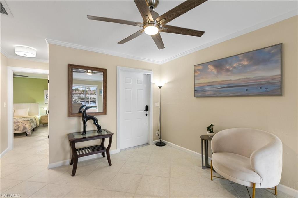 Living area with ornamental molding, a ceiling fan, and light tile patterned floors