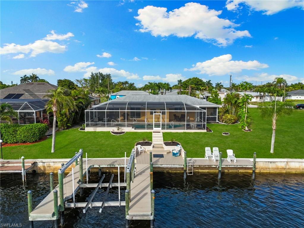 Dock area featuring a sunroom, a lanai, a water view, and a lawn
