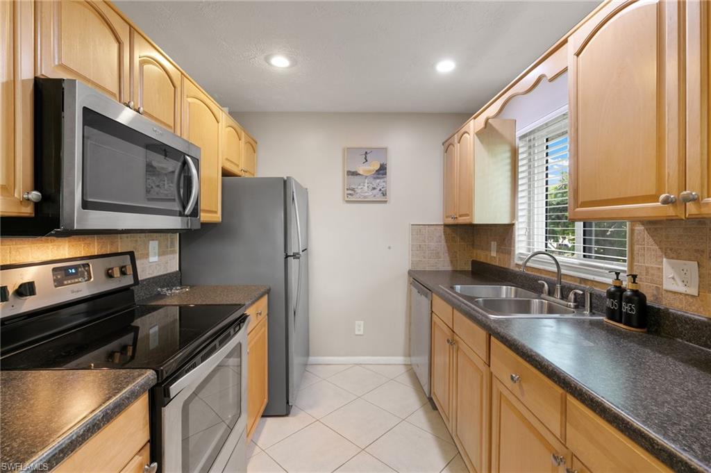 Kitchen with stainless steel appliances, backsplash, dark countertops, and recessed lighting