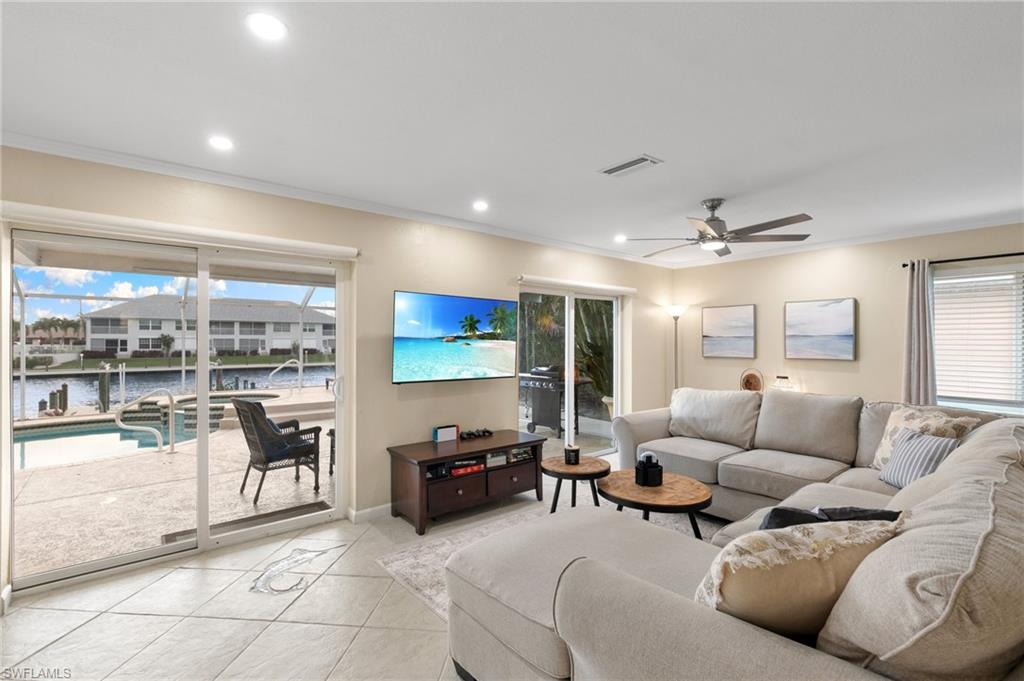 Living room featuring tile patterned flooring, ornamental molding, a ceiling fan, recessed lighting, and a sunroom