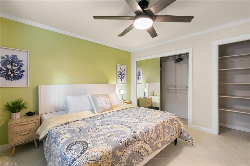 Bedroom featuring crown molding, two closets, light tile patterned floors, and a ceiling fan