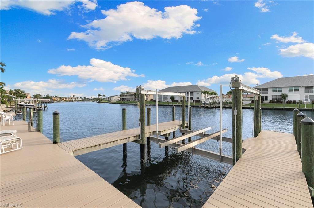 Dock area with boat lift, a water view, and a residential view