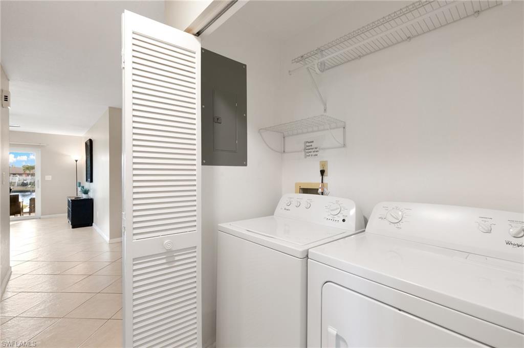Laundry room featuring light tile patterned flooring, electric panel, and washer and dryer