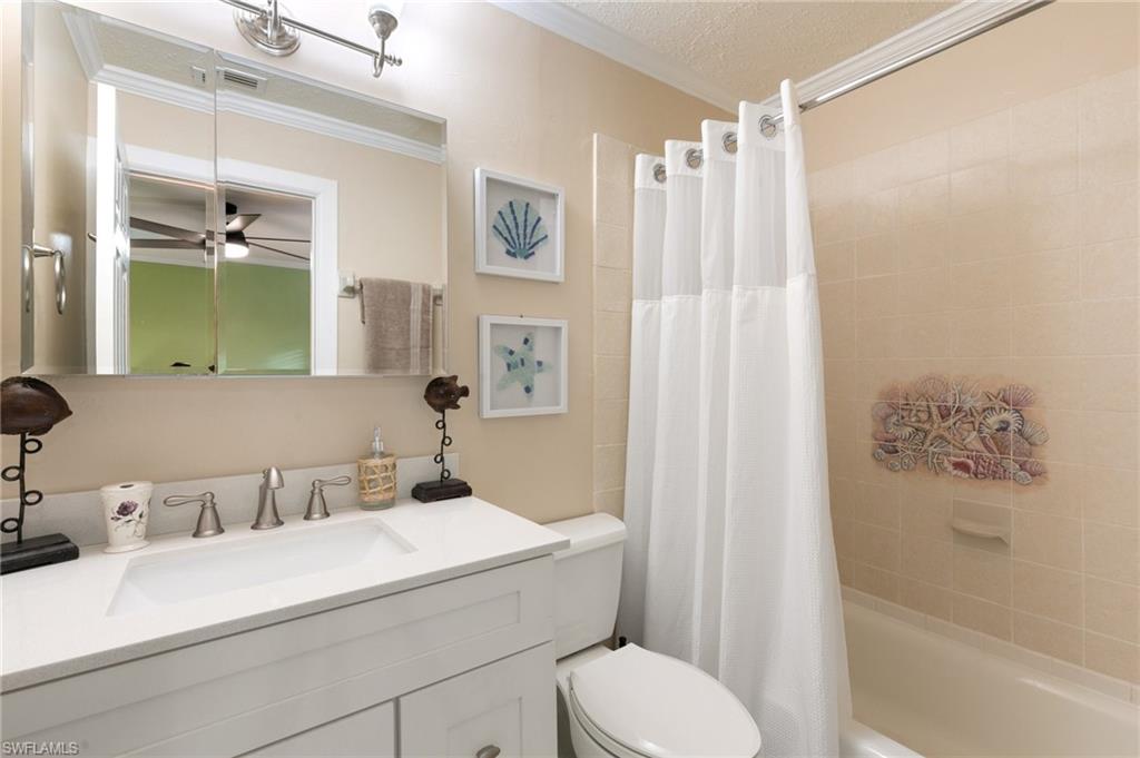 Bathroom with vanity, shower / bath combo with shower curtain, crown molding, a textured ceiling, and ceiling fan