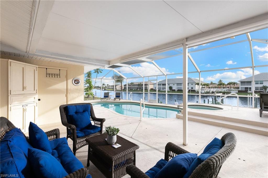 View of swimming pool featuring glass enclosure, a patio area, a sunroom, a water view, and outdoor lounge area