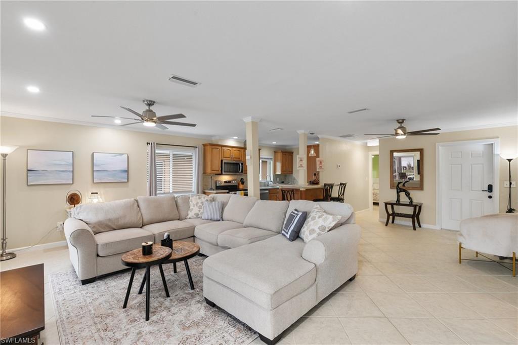 Living area with a ceiling fan, crown molding, light tile patterned floors, and recessed lighting