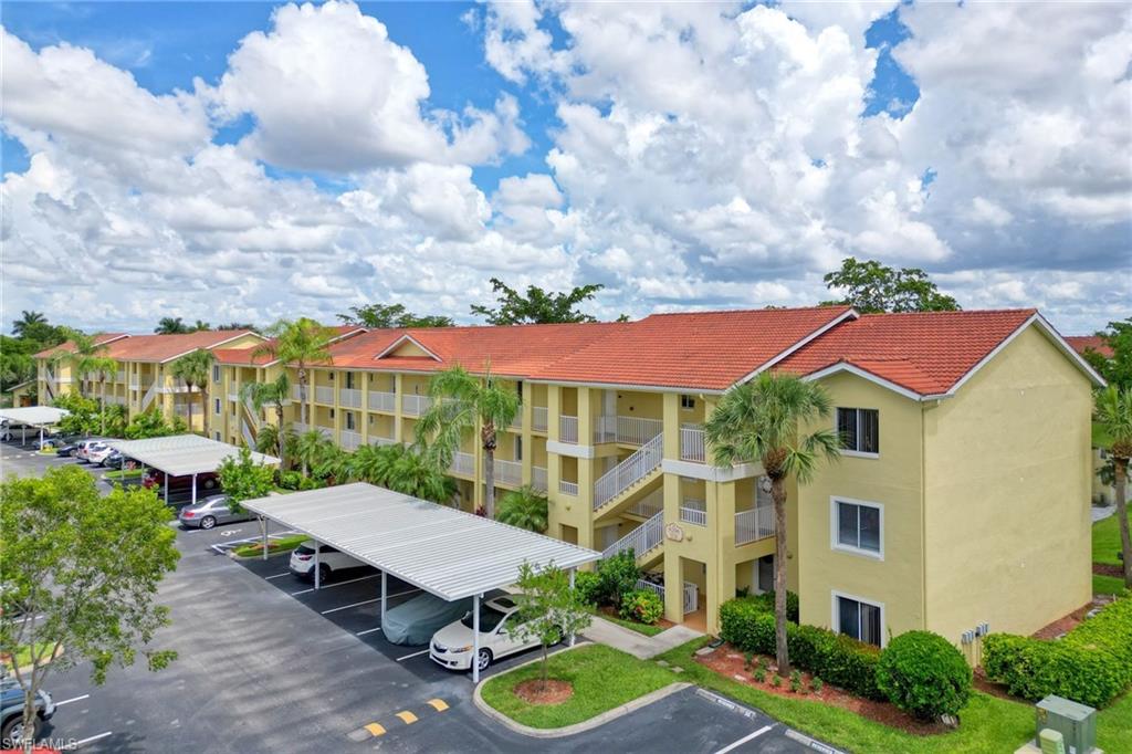 View of apartment building / complex with covered and uncovered parking