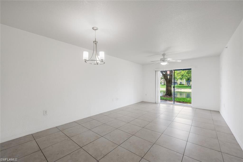 Tiled empty room with a chandelier and a ceiling fan