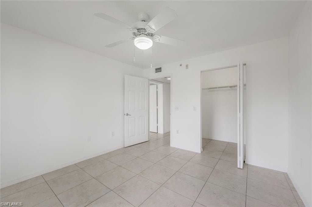 Unfurnished bedroom featuring a ceiling fan, light tile patterned floors, and a closet