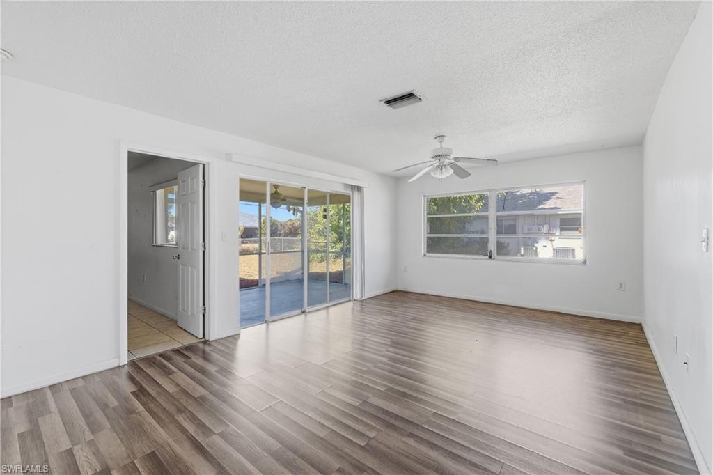 Unfurnished room with a ceiling fan, wood finished floors, and a textured ceiling