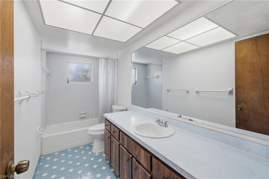 Full bathroom with shower / bath combo with shower curtain, vanity, and light tile patterned floors