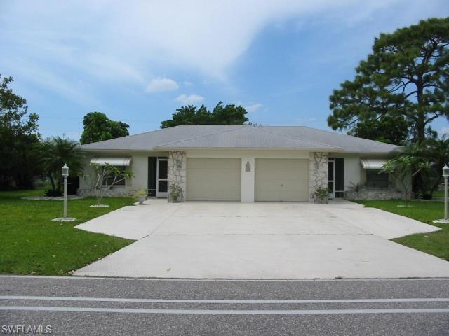View of front of property featuring stone siding, concrete driveway, and a yard