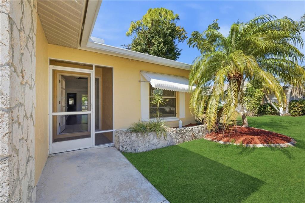 Property entrance featuring a yard, stucco siding, and a sunroom