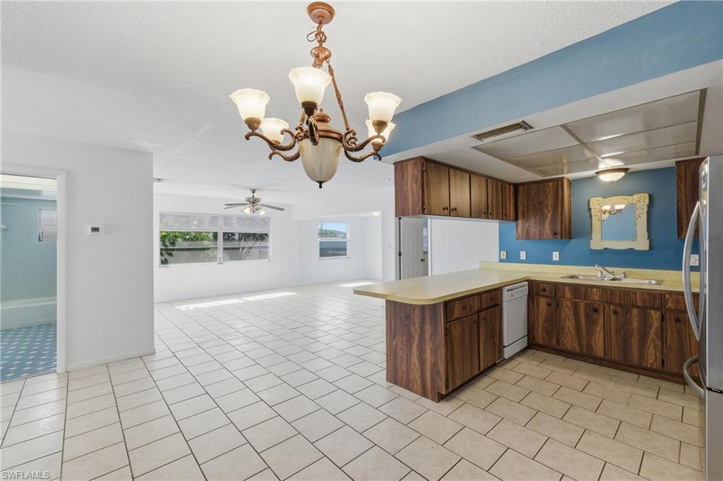 Kitchen featuring hanging lights, light countertops, a ceiling fan, a peninsula, and open floor plan