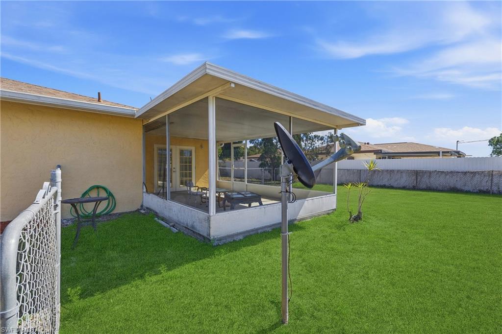 Back of property with a fenced backyard, a sunroom, and stucco siding