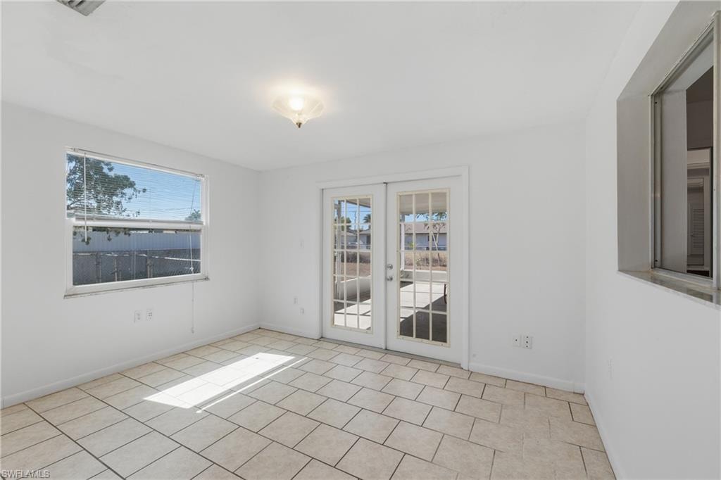 Empty room featuring french doors and light tile patterned flooring