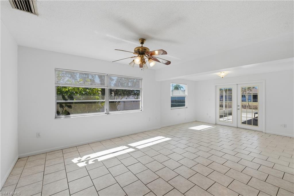 Empty room with french doors, ceiling fan, and a textured ceiling