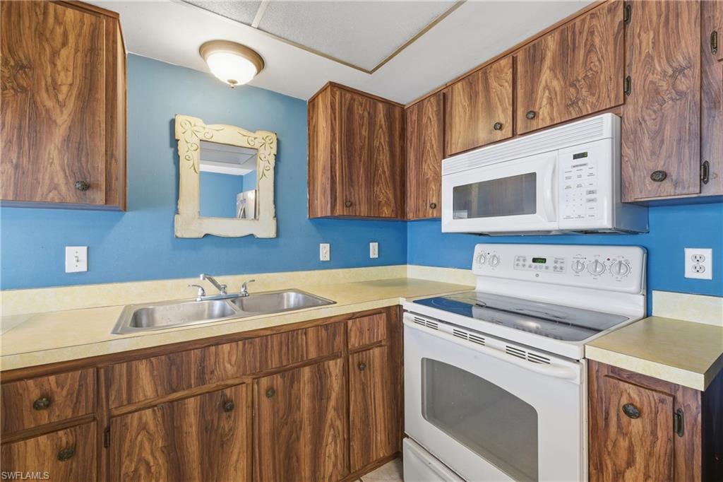Kitchen featuring white appliances, light countertops, and wood finish cabinetry