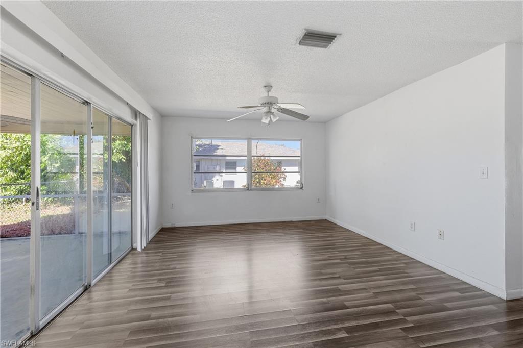 Empty room featuring ceiling fan, dark wood-style flooring, and a textured ceiling