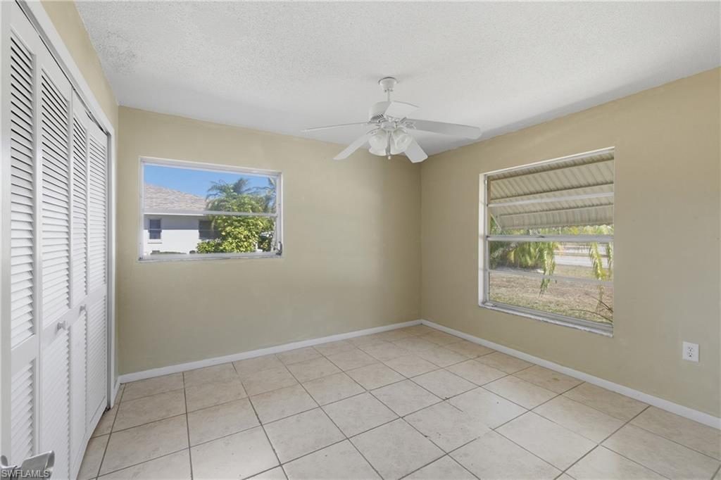 Unfurnished bedroom featuring a closet, ceiling fan, a textured ceiling, and light tile patterned floors