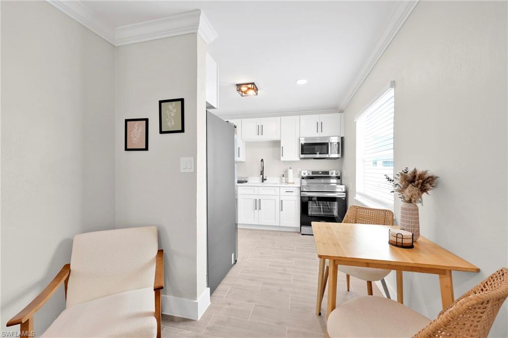 Kitchen featuring appliances with stainless steel finishes, light countertops, ornamental molding, and white cabinetry