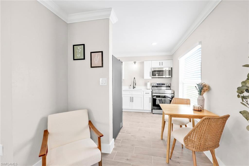 Kitchen featuring white cabinetry, crown molding, light countertops, stainless steel appliances, and wood finish floors