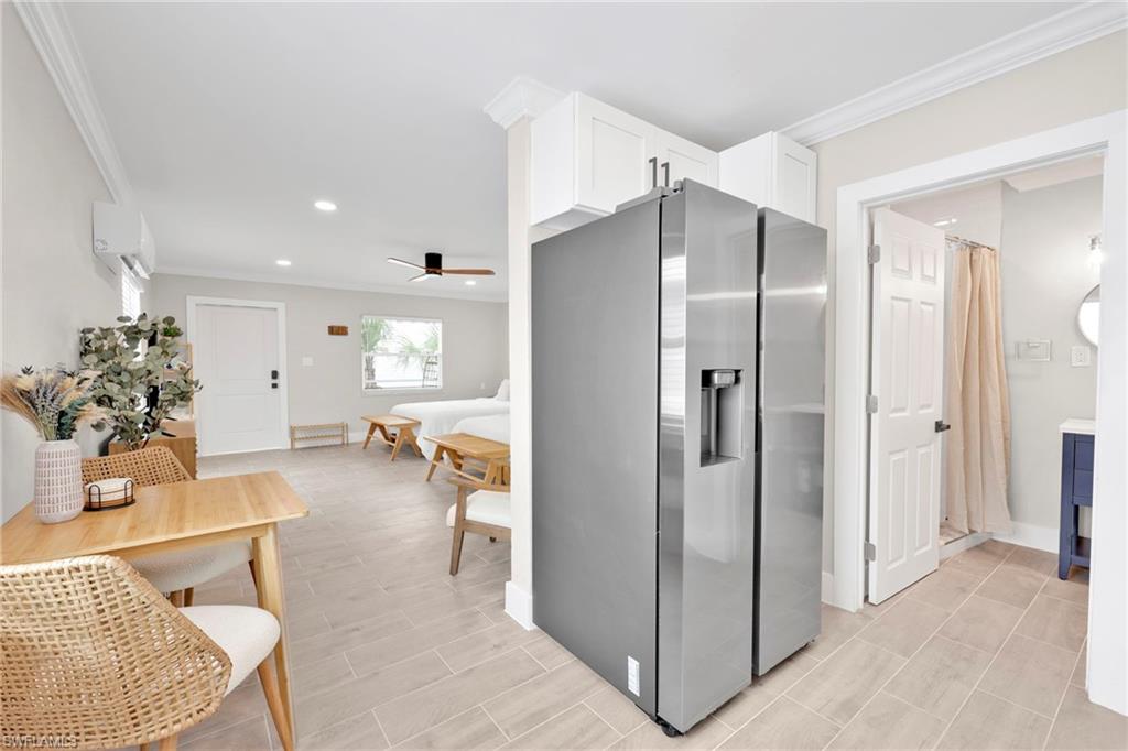 Kitchen with stainless steel fridge, crown molding, ceiling fan, recessed lighting, and white cabinets