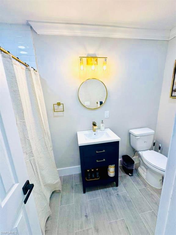 Bathroom with a shower with curtain, wood finish floors, vanity, and ornamental molding