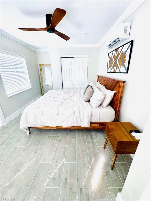 Bedroom featuring wood finish floors, a closet, crown molding, a ceiling fan, and a wall mounted air conditioner