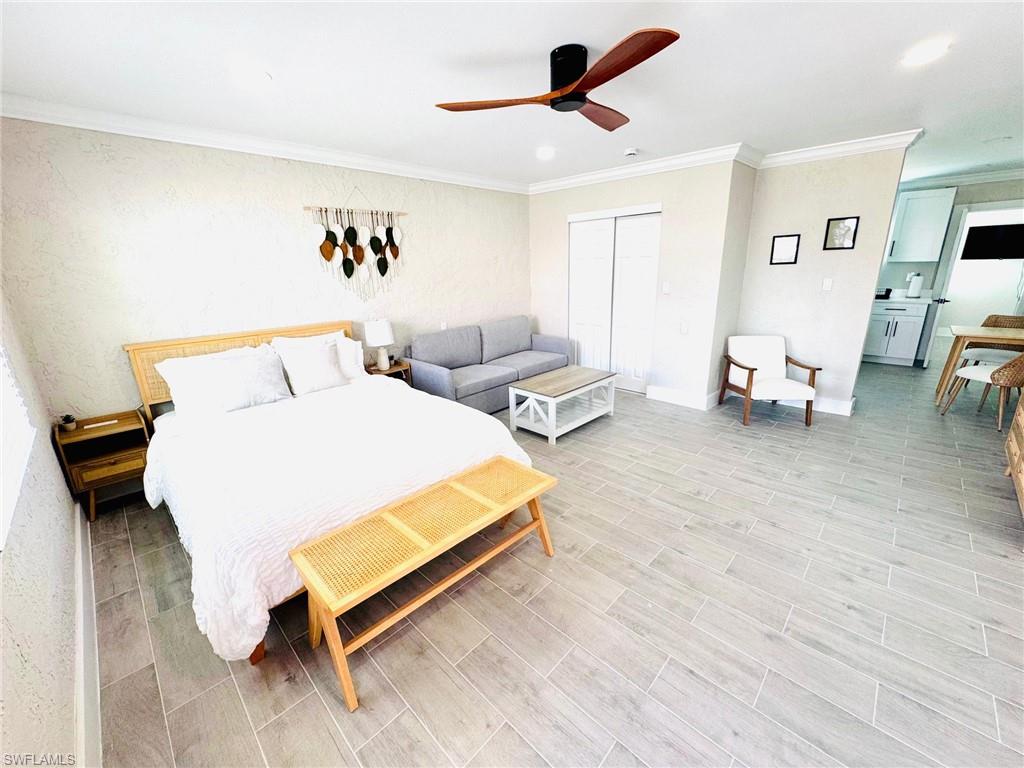Bedroom with crown molding, wood tiled floors, ceiling fan, a closet, and recessed lighting