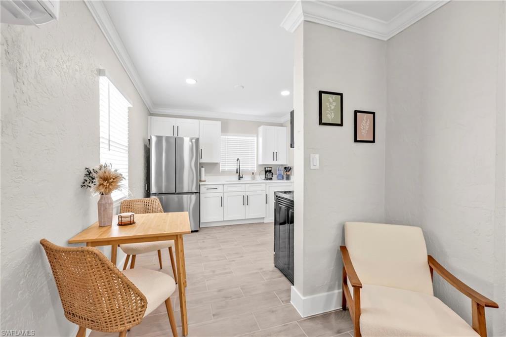 Kitchen featuring white cabinetry, crown molding, freestanding refrigerator, and a textured wall